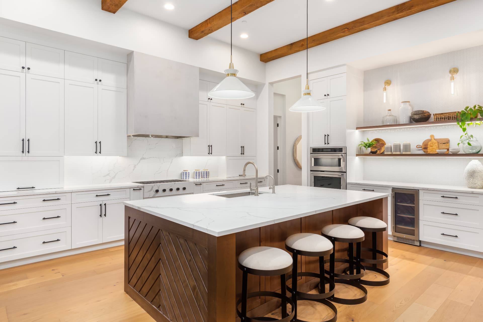 Bright white kitchen with marble island, exposed wood beams and pendant lighting